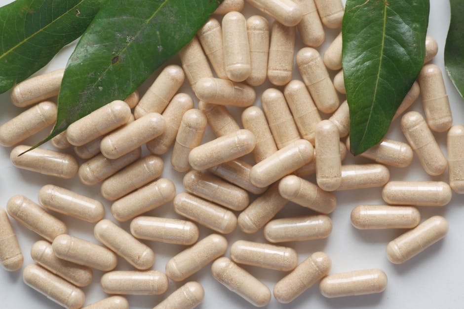 Cápsulas de suplemento natural junto a hojas verdes