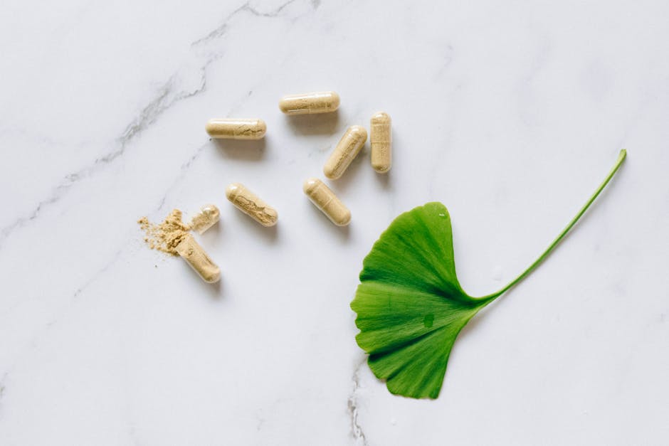 Cápsulas de suplemento natural sobre mármol blanco con hoja verde